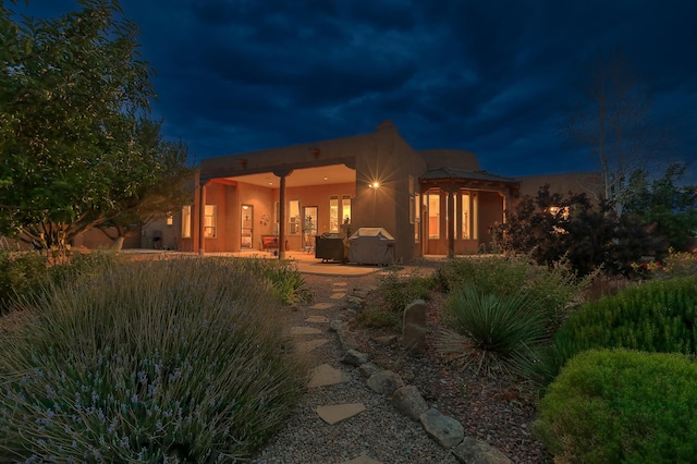 back house at night featuring a patio area