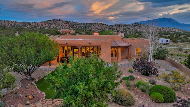 back house at dusk featuring a patio and a mountain view