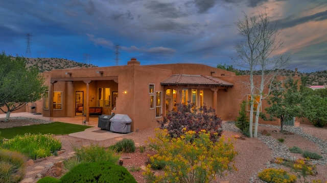 back house at dusk featuring a patio