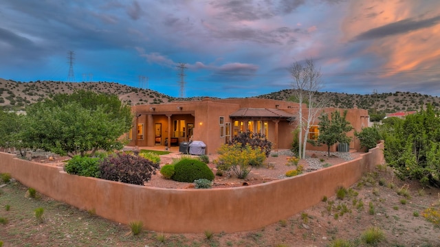 back house at dusk with a mountain view and a patio area