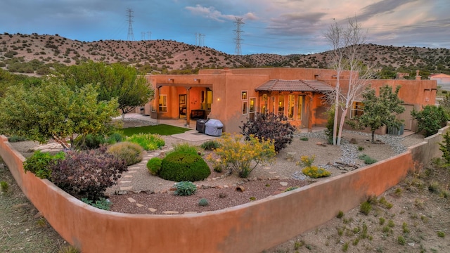 yard at dusk featuring a mountain view and a patio area