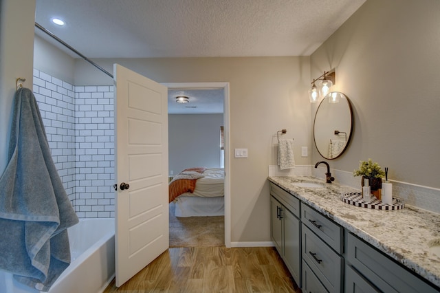 bathroom with washtub / shower combination, hardwood / wood-style floors, vanity, and a textured ceiling