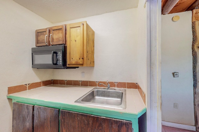 kitchen with sink, a textured ceiling, and tile countertops