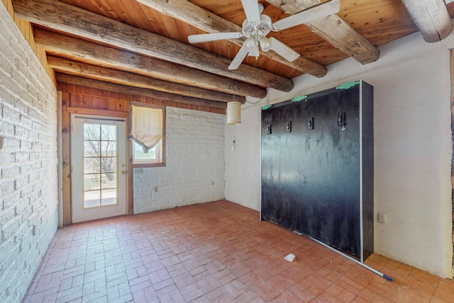 unfurnished room with brick wall, wooden ceiling, and ceiling fan