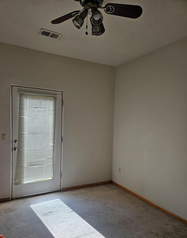 carpeted empty room featuring ceiling fan and a textured ceiling