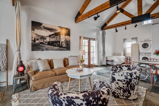 living room featuring high vaulted ceiling, beamed ceiling, stacked washer and clothes dryer, and a healthy amount of sunlight