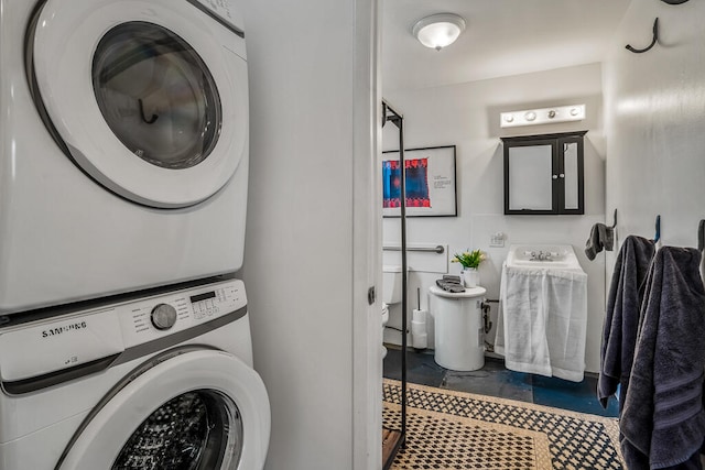 clothes washing area with tile patterned floors and stacked washer / drying machine