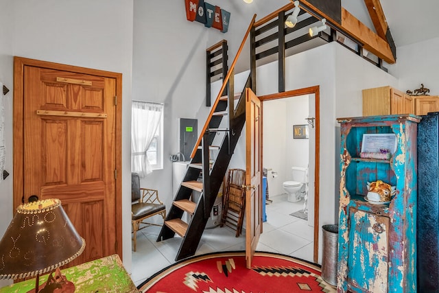 tiled bedroom featuring ensuite bath, lofted ceiling, and electric panel