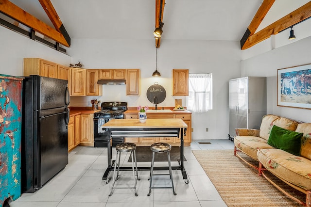 kitchen featuring black appliances, hanging light fixtures, beam ceiling, light tile patterned floors, and track lighting