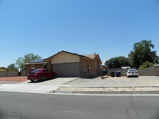 single story home featuring brick siding, an attached garage, fence, and driveway