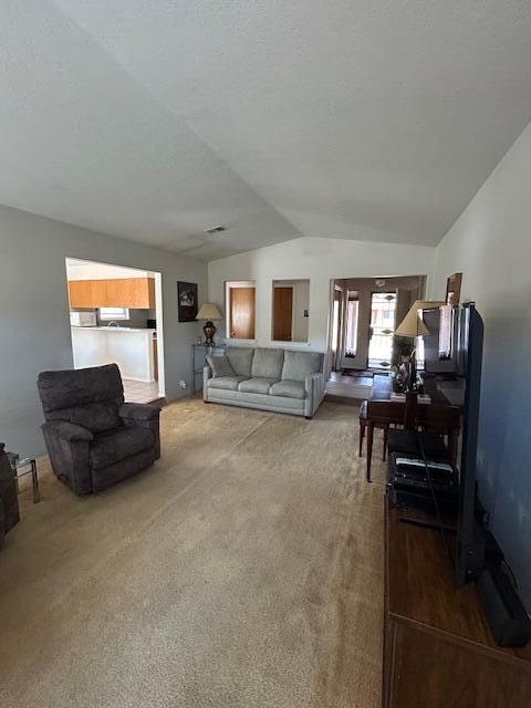 carpeted living room featuring vaulted ceiling