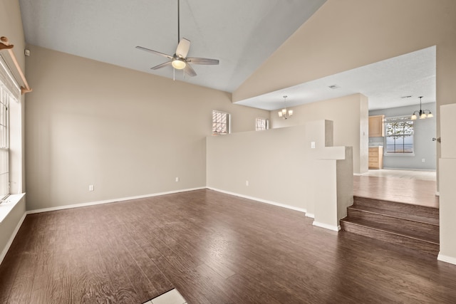 spare room with dark wood-type flooring, ceiling fan with notable chandelier, and high vaulted ceiling