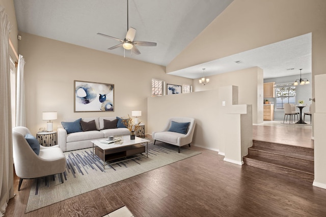 living room with dark wood-type flooring, lofted ceiling, and ceiling fan with notable chandelier