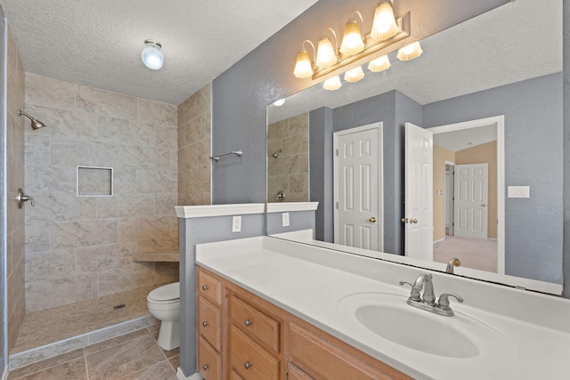 bathroom featuring tiled shower, tile patterned floors, toilet, a textured ceiling, and vanity