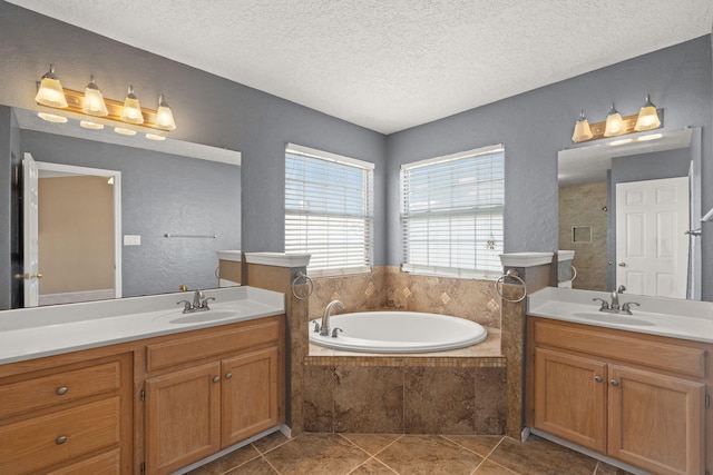 bathroom featuring tile patterned flooring, vanity, a textured ceiling, and a relaxing tiled tub