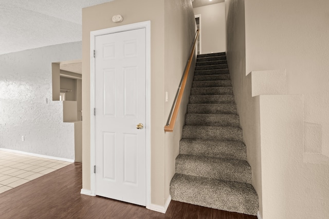 stairs with a textured ceiling and hardwood / wood-style flooring