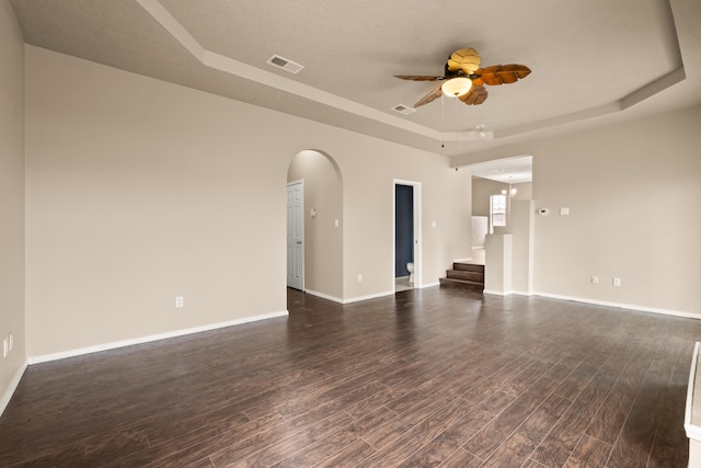 spare room featuring dark wood-type flooring, a textured ceiling, ceiling fan, and a raised ceiling