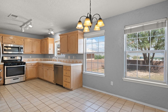 kitchen with a wealth of natural light, appliances with stainless steel finishes, and hanging light fixtures