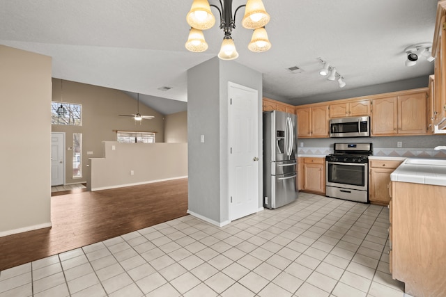 kitchen featuring stainless steel appliances, light hardwood / wood-style floors, ceiling fan with notable chandelier, pendant lighting, and vaulted ceiling