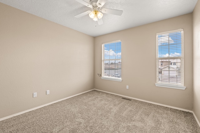 carpeted spare room featuring a textured ceiling and ceiling fan