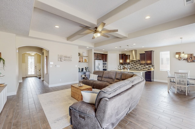 living room with light wood-style floors, beamed ceiling, and baseboards