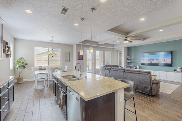 kitchen with wood finish floors, visible vents, a sink, and stainless steel dishwasher