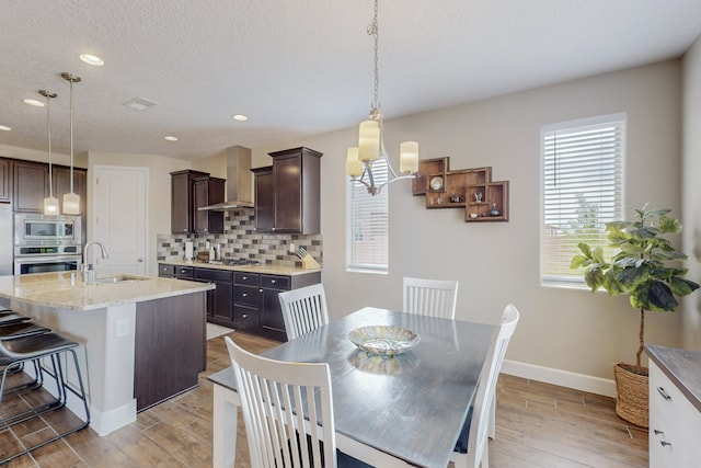 dining area with light wood-type flooring, baseboards, a textured ceiling, and recessed lighting