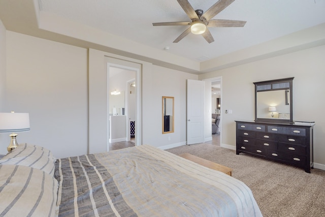 bedroom with a raised ceiling, light carpet, ceiling fan, and baseboards