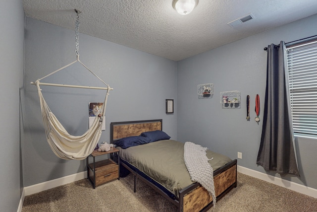 bedroom with a textured ceiling, carpet flooring, visible vents, and baseboards