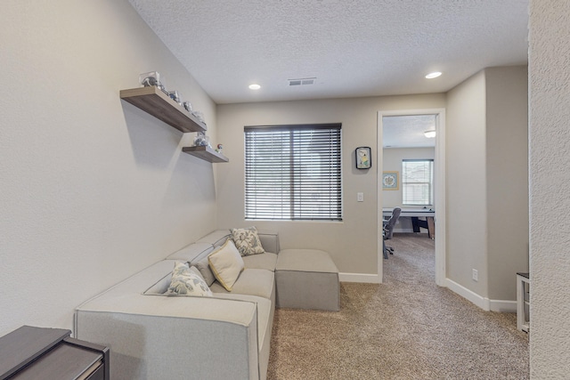 living area featuring a textured ceiling, carpet floors, visible vents, and baseboards