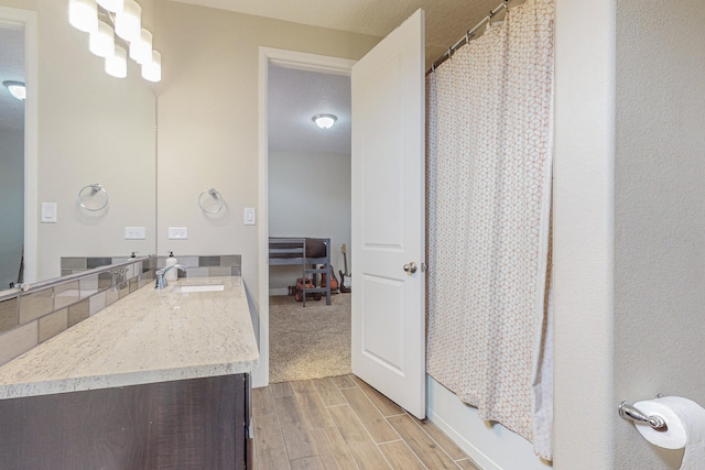 full bathroom featuring a textured ceiling, wood finish floors, and vanity