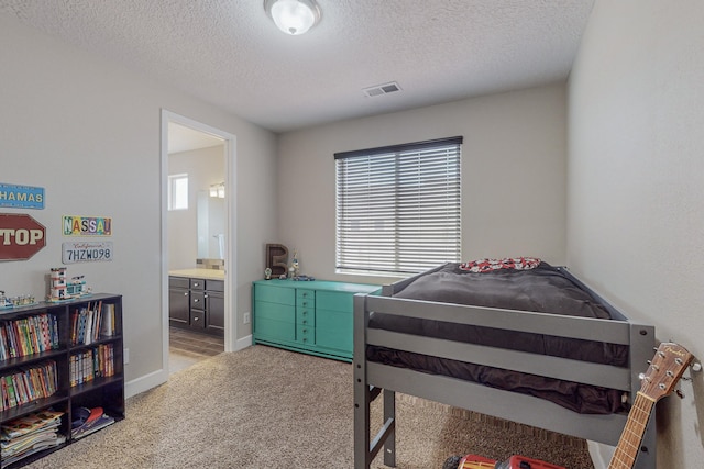 carpeted bedroom with a textured ceiling, multiple windows, visible vents, and connected bathroom