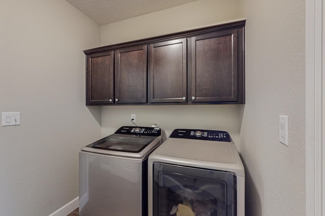 laundry area with cabinet space, washer and clothes dryer, baseboards, and a textured ceiling