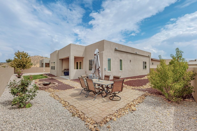 rear view of property with a patio, an outdoor fire pit, a fenced backyard, and stucco siding