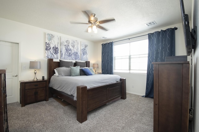 carpeted bedroom with ceiling fan and a textured ceiling