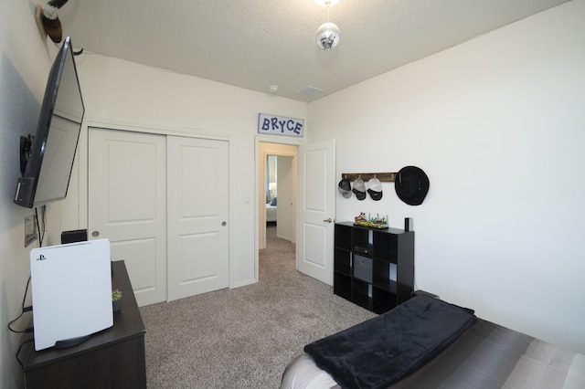 carpeted bedroom featuring a textured ceiling and a closet