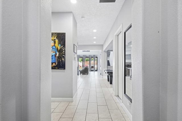 hall featuring a textured ceiling and light tile patterned flooring