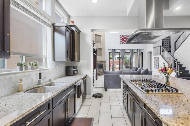 kitchen featuring light stone countertops, sink, stainless steel appliances, backsplash, and dark brown cabinets