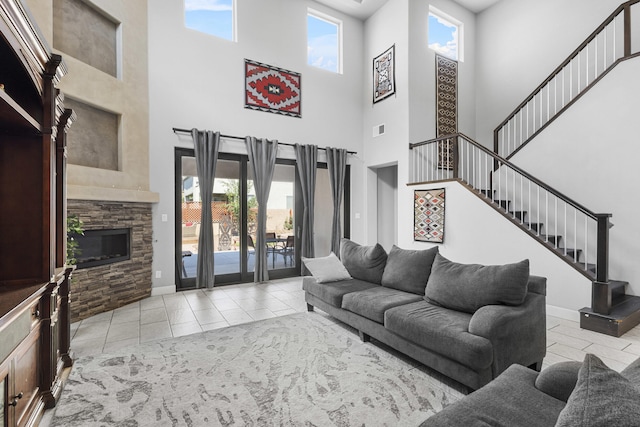 living room with a stone fireplace, light tile patterned floors, and a high ceiling