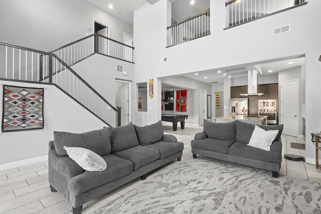 living room featuring pool table, light tile patterned floors, and a high ceiling