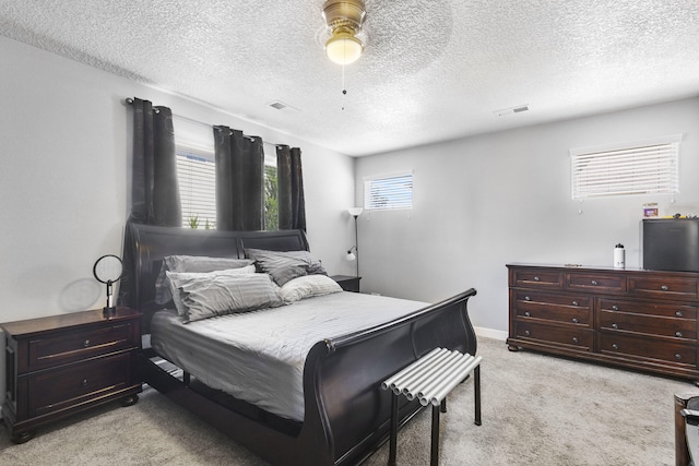 bedroom featuring ceiling fan, light colored carpet, and a textured ceiling