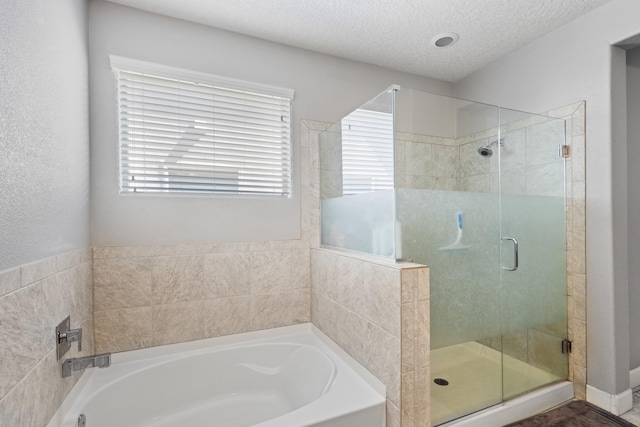 bathroom with a textured ceiling and separate shower and tub