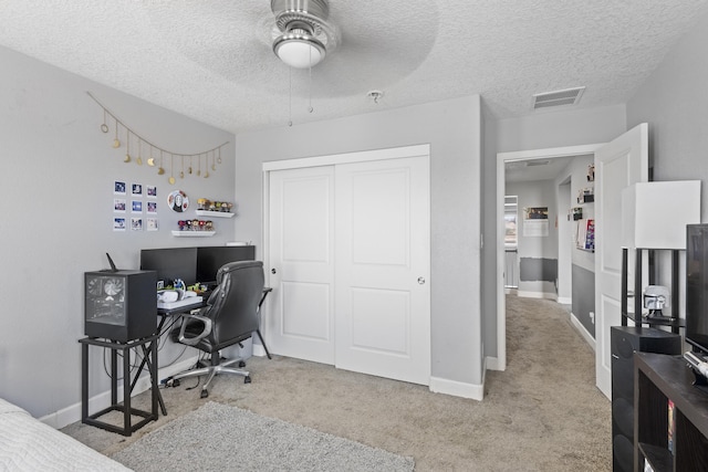 carpeted bedroom featuring ceiling fan, a closet, and a textured ceiling