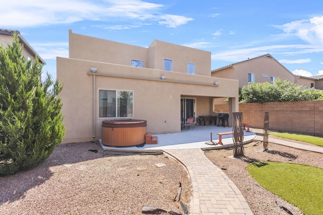 rear view of house featuring a patio area and a hot tub