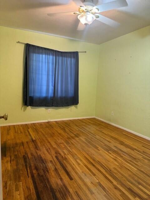 empty room with ceiling fan, baseboards, and wood finished floors