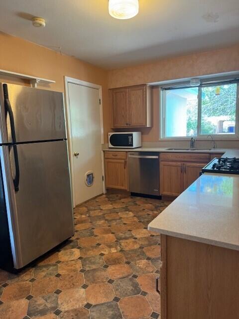 kitchen with a sink, stainless steel appliances, and light countertops