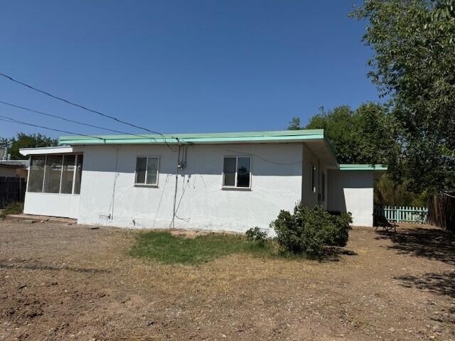 view of side of home with a sunroom, fence, and stucco siding