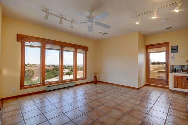 empty room featuring light tile patterned flooring, track lighting, and baseboard heating