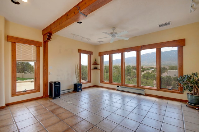 unfurnished living room featuring a healthy amount of sunlight, beamed ceiling, baseboard heating, and light tile patterned floors