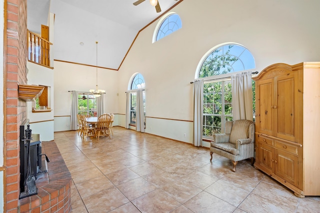 living area featuring ceiling fan with notable chandelier, high vaulted ceiling, and light tile patterned flooring